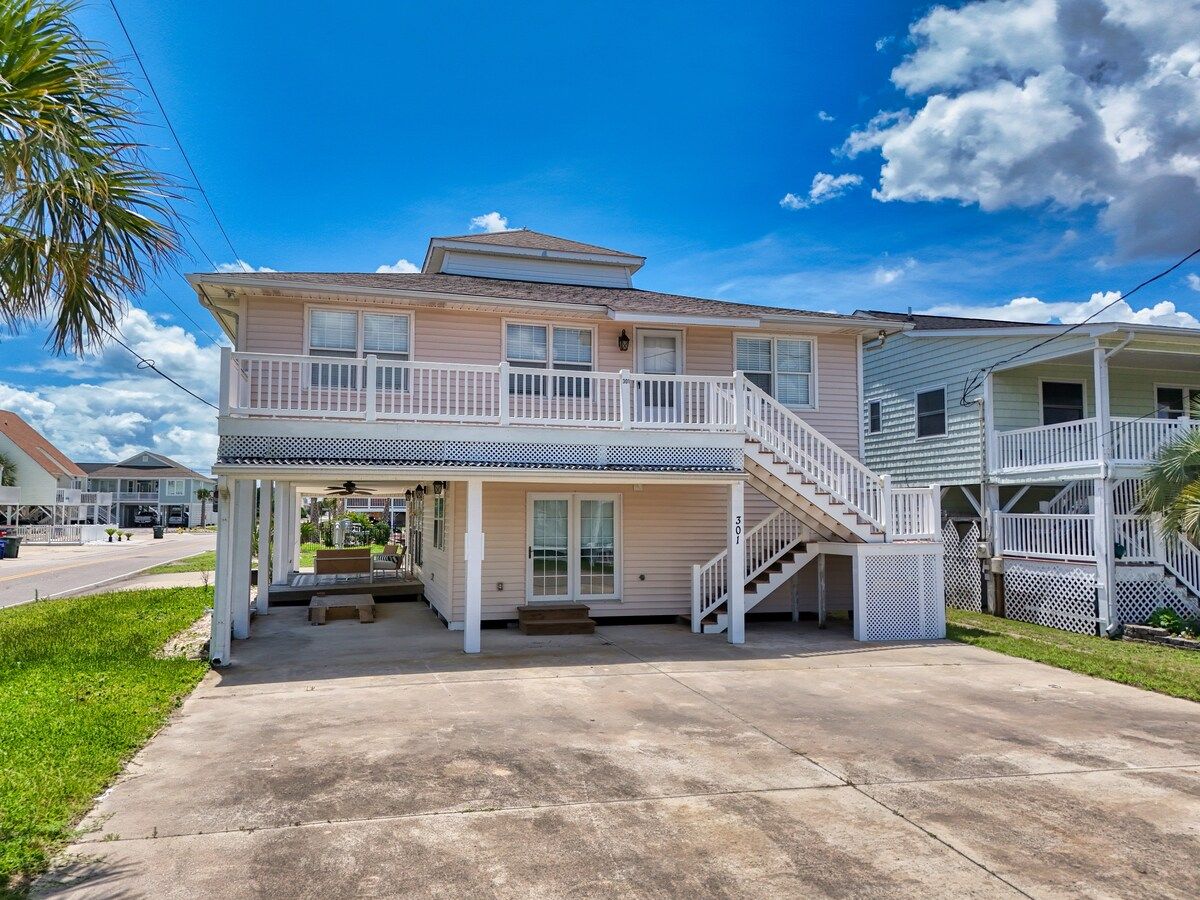 A two-story house with a balcony, a covered porch, and a staircase leading to the upper level.