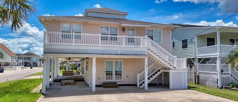 A two-story house with a balcony, a covered porch, and a staircase leading to the upper level.