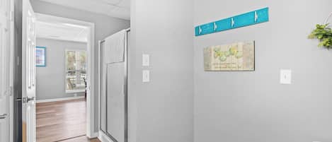 A hallway with a door leading to a bathroom, a wall-mounted towel rack, and a framed artwork.