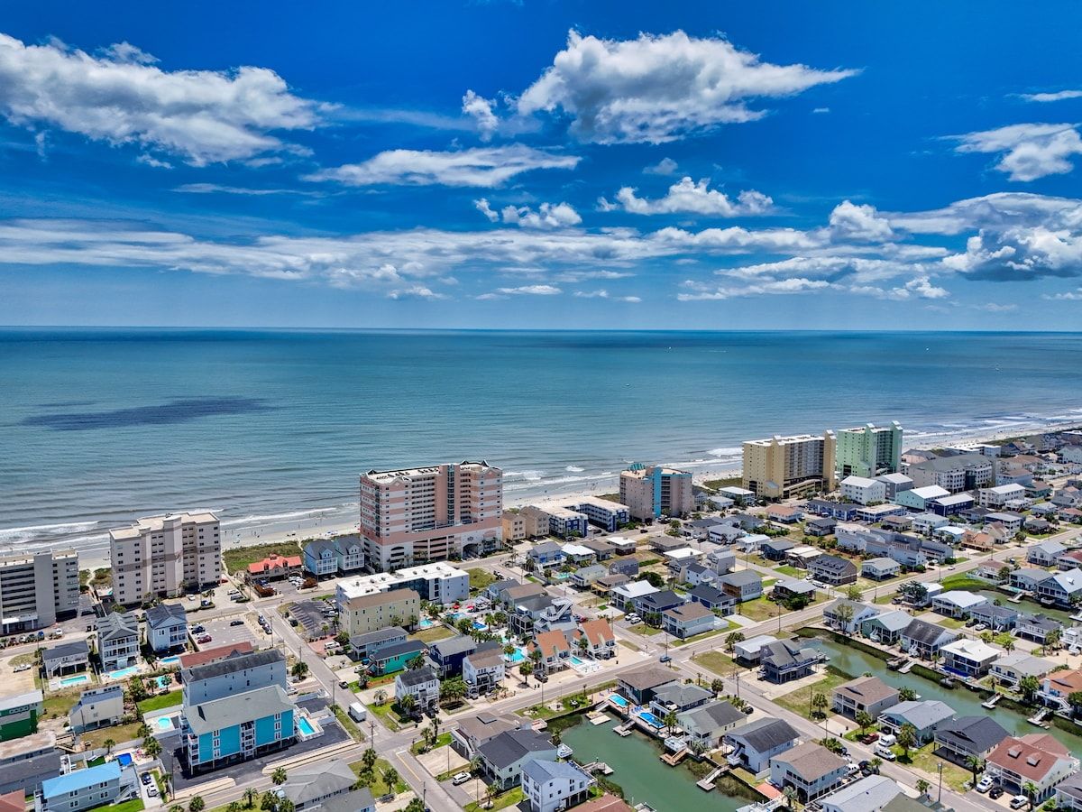 Une zone résidentielle côtière comprenant des immeubles, une plage et un port de plaisance.