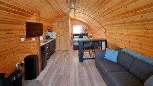 A cozy, wooden interior with a kitchen, dining area, and seating space.