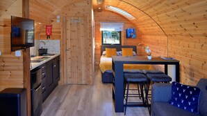 Ein gemütlicher, holzgetäfelter Innenraum mit einer Küche, Essbereich und einem Bett.