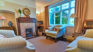 A cozy living room with a fireplace, comfortable seating, and a large window with curtains. - Bryn Tor (Bolsover)