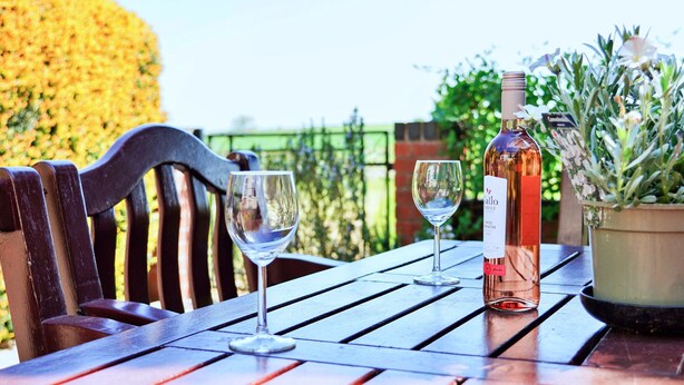 A wooden table with two wine glasses and a bottle of rosé wine. - Bryn Tor (Bolsover)