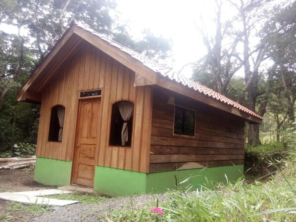 A small wooden cabin with a green base, a single door, and two windows. - Monteverde Romantic Cottage (Monteverde)