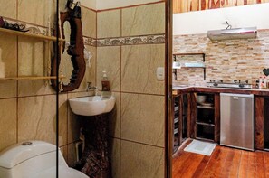 A bathroom with a sink, toilet, and a shower area. - Monteverde Romantic Cottage (Monteverde)