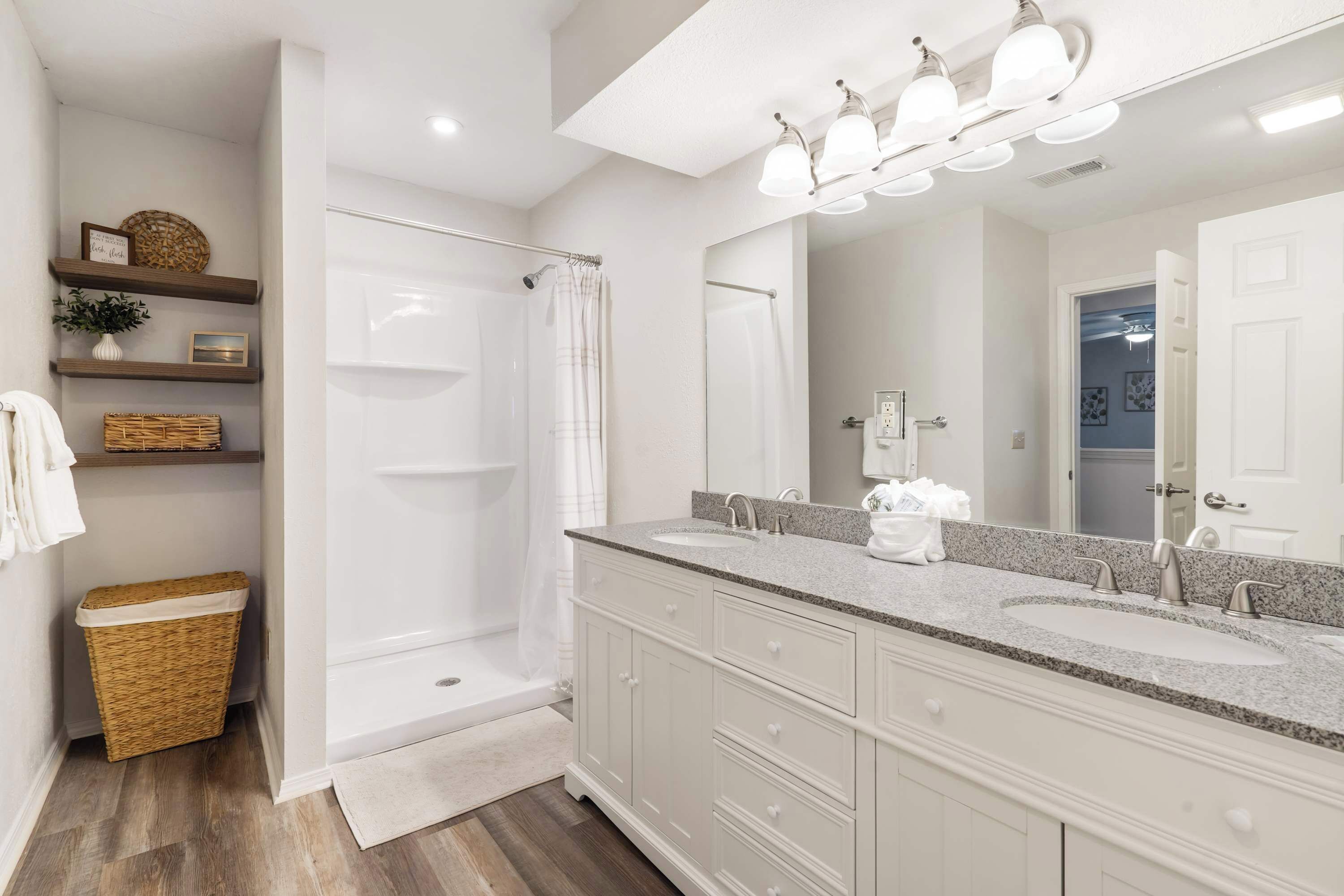 A modern bathroom with a walk-in shower, two sinks, and a large mirror.