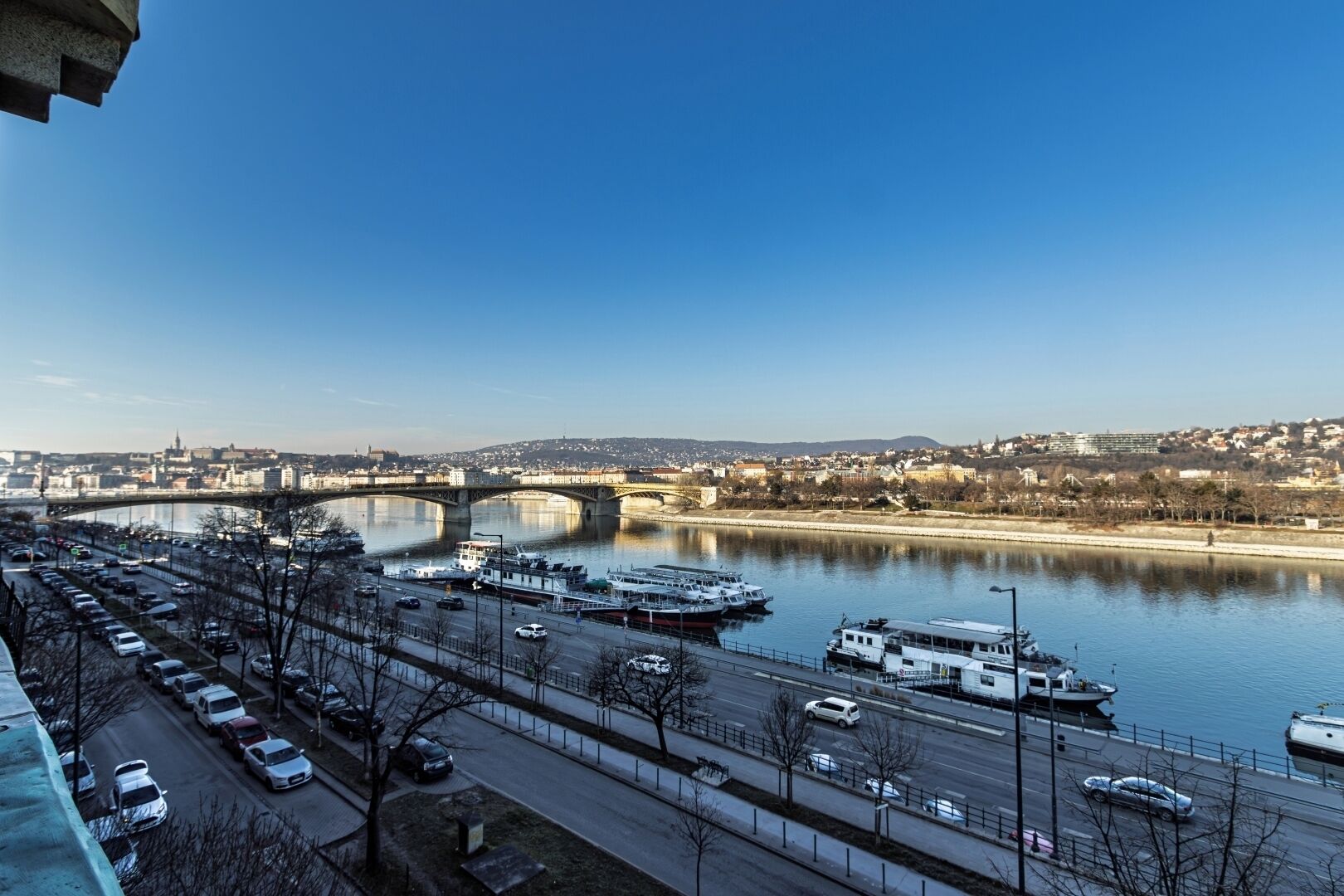 Ein Fluss mit Booten, einer Brücke und einer Stadtlandschaft im Hintergrund.