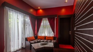 A modern living room with a sectional sofa, a coffee table, and a red carpet leading to a door.
