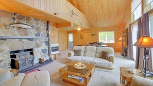 A cozy cabin interior with a stone fireplace, wooden ceiling, and a comfortable seating area. - Escanaba River Getaway: Fish, Hike & Ski! (Cornell)