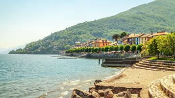 A coastal town with buildings along the waterfront, a stone staircase leading down to the beach, and a hill in the background.