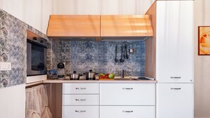 A compact kitchen with white cabinets, a built-in oven, and a tiled backsplash. - Civico 72 Monopoli (Monopoli)