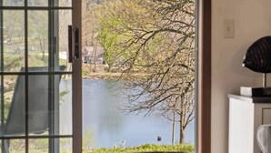 Une pièce avec vue sur un lac, une chaise et une table.