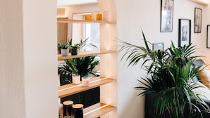 A modern interior with wooden shelves, potted plants, and framed artwork on the wall. - Apartment 'Fewo Tauberblick' with Shared Terrace, Private Garden and Wi-Fi (Röttingen)