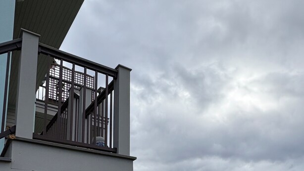 Ein modernes Haus mit einem Balkon mit Blick auf eine felsige Küstenlinie.
