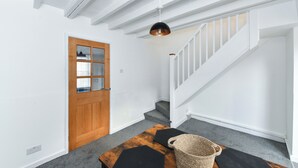 Ein Korridor mit einer Holztür, einer Treppe und einer Hängelampe.