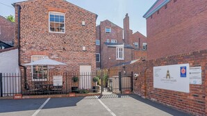 A brick building with a gated entrance, a sign for City Cottages, and a parking area. - Luxury Apartment, City Break, 4A City Cottage Central Chester (Chester)