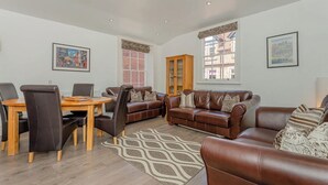 A spacious living room with a wooden dining table, leather sofas, and a patterned rug. - Luxury Apartment, City Break, 4A City Cottage Central Chester (Chester)