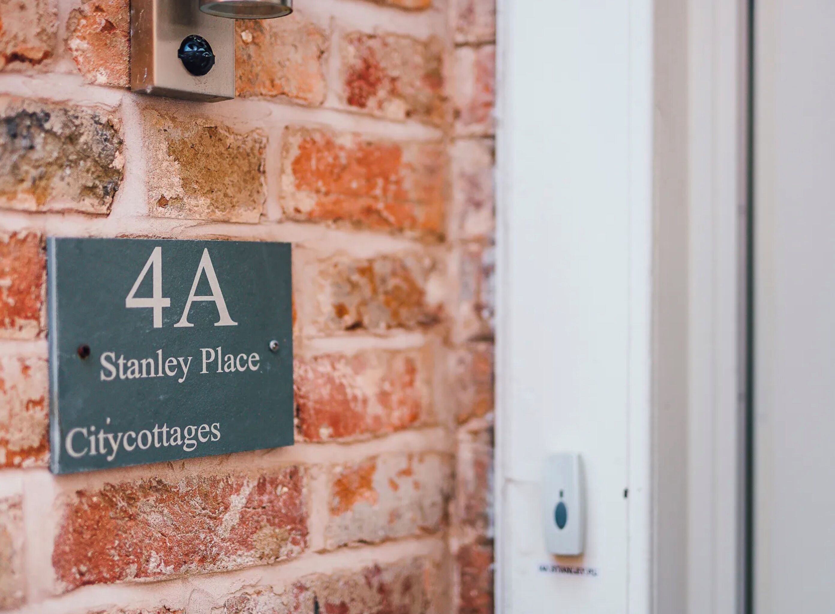 Un mur de briques sur lequel est apposée une plaque indiquant « 4A, rue Stanley, Citycottages ».