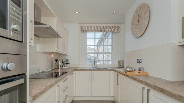 A modern kitchen with white cabinetry, a built-in oven, a stainless steel range hood, and a large window with a striped valance. - Luxury Apartment, City Break, 4A City Cottage Central Chester (Chester)