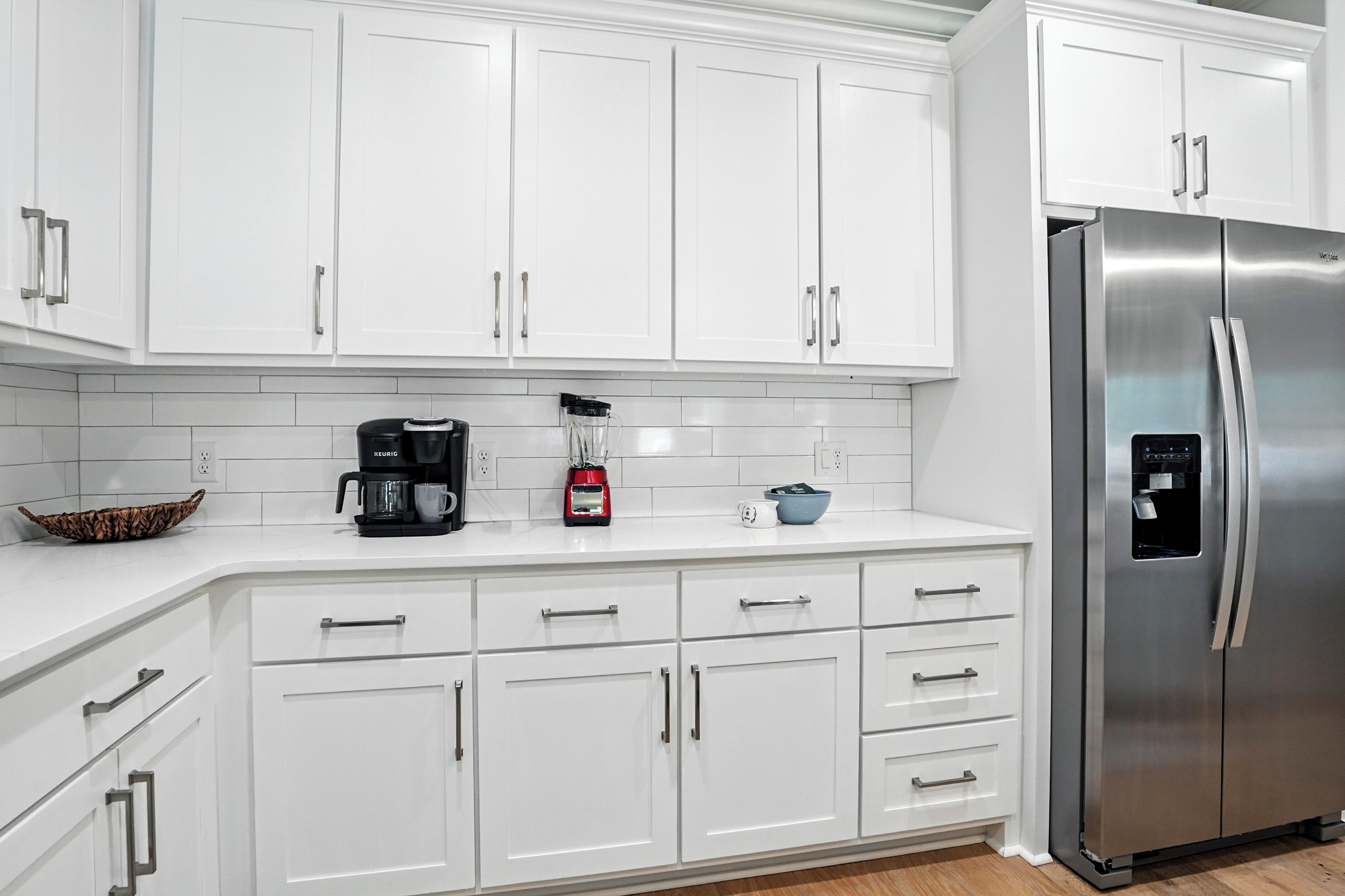 A modern kitchen with white cabinets, stainless steel appliances, and a built-in coffee maker.