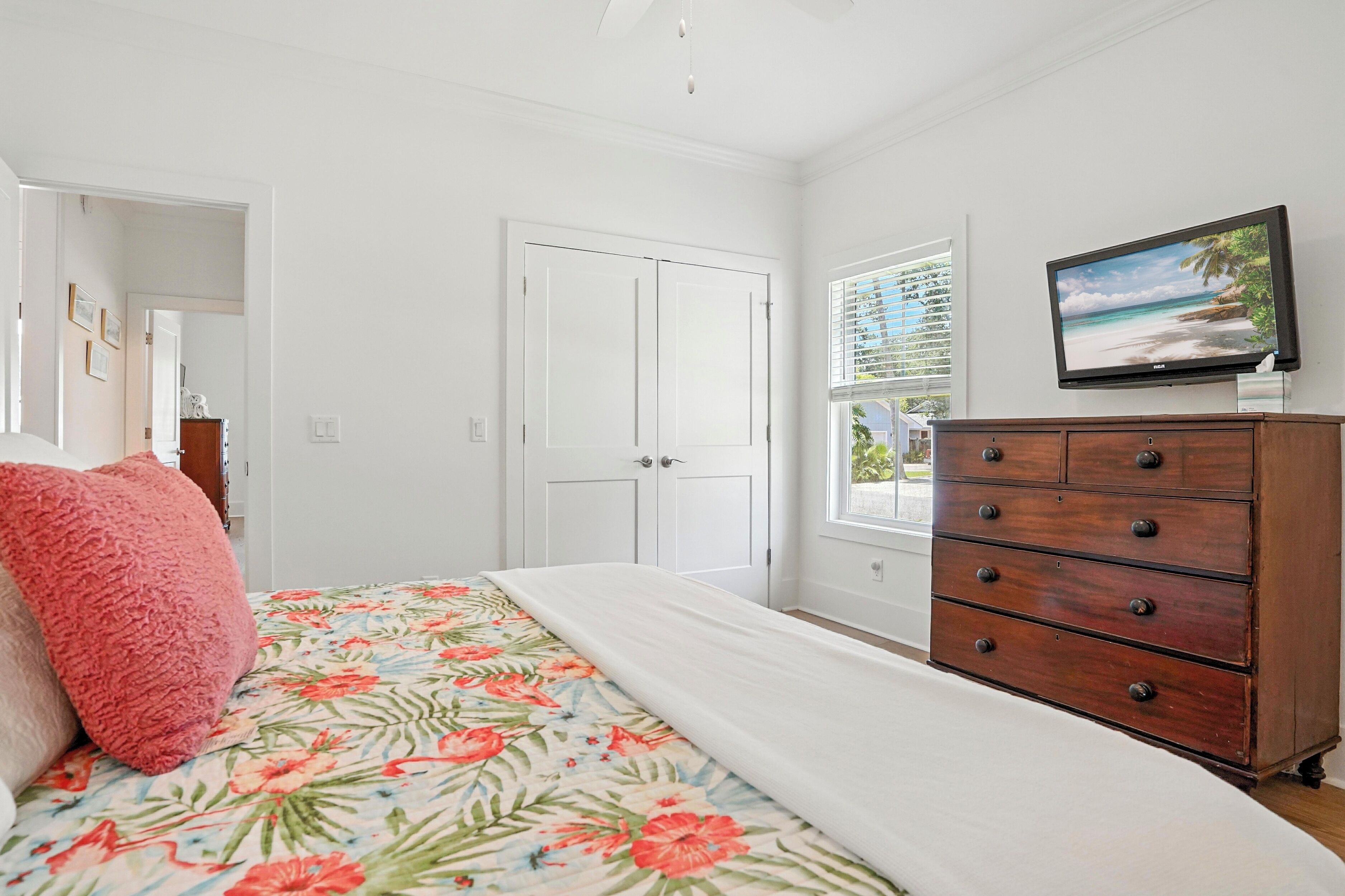 A bedroom with a bed, a dresser, a television, and a door.