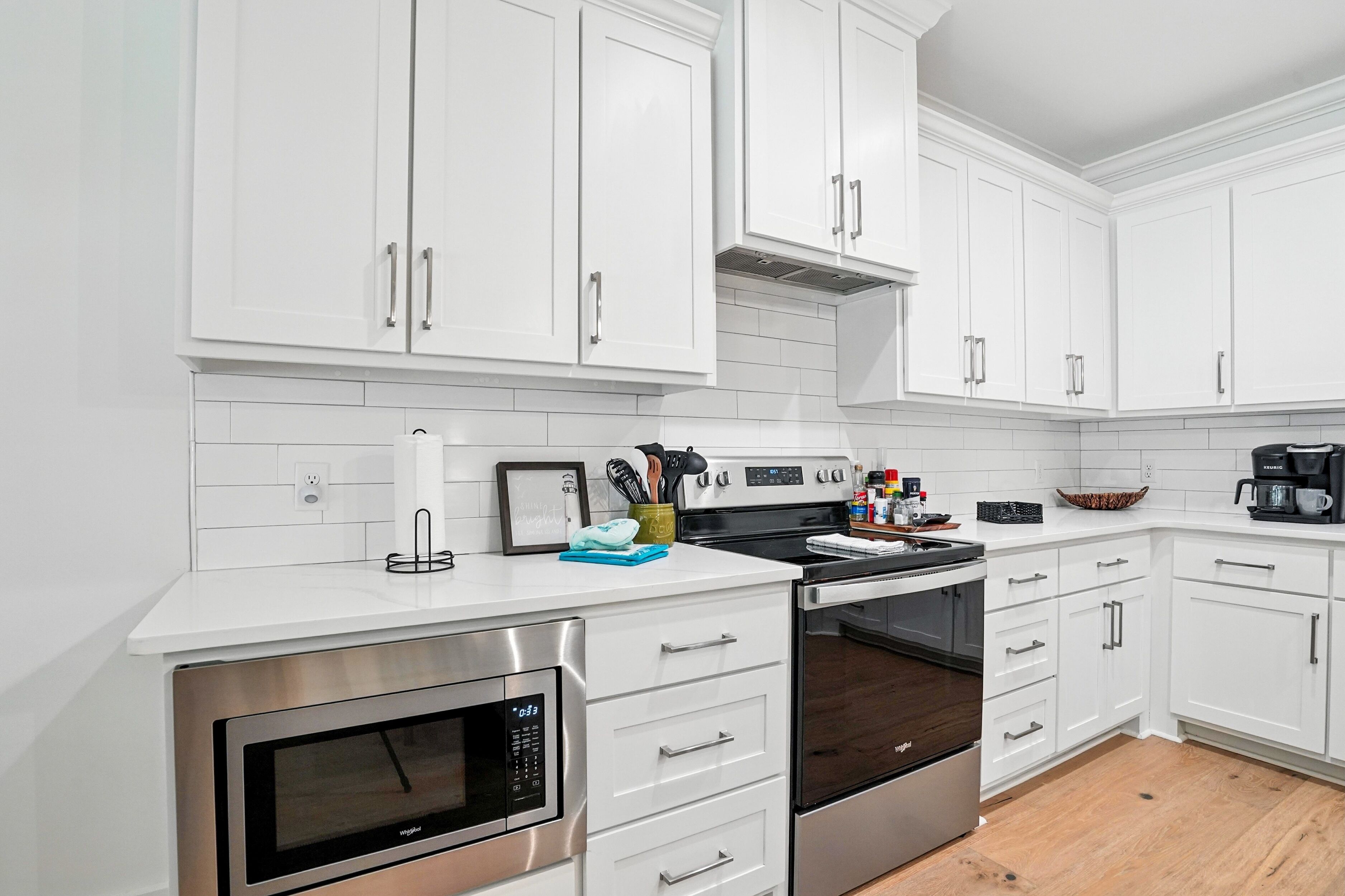 A modern kitchen with white cabinets, stainless steel appliances, and a tiled backsplash.