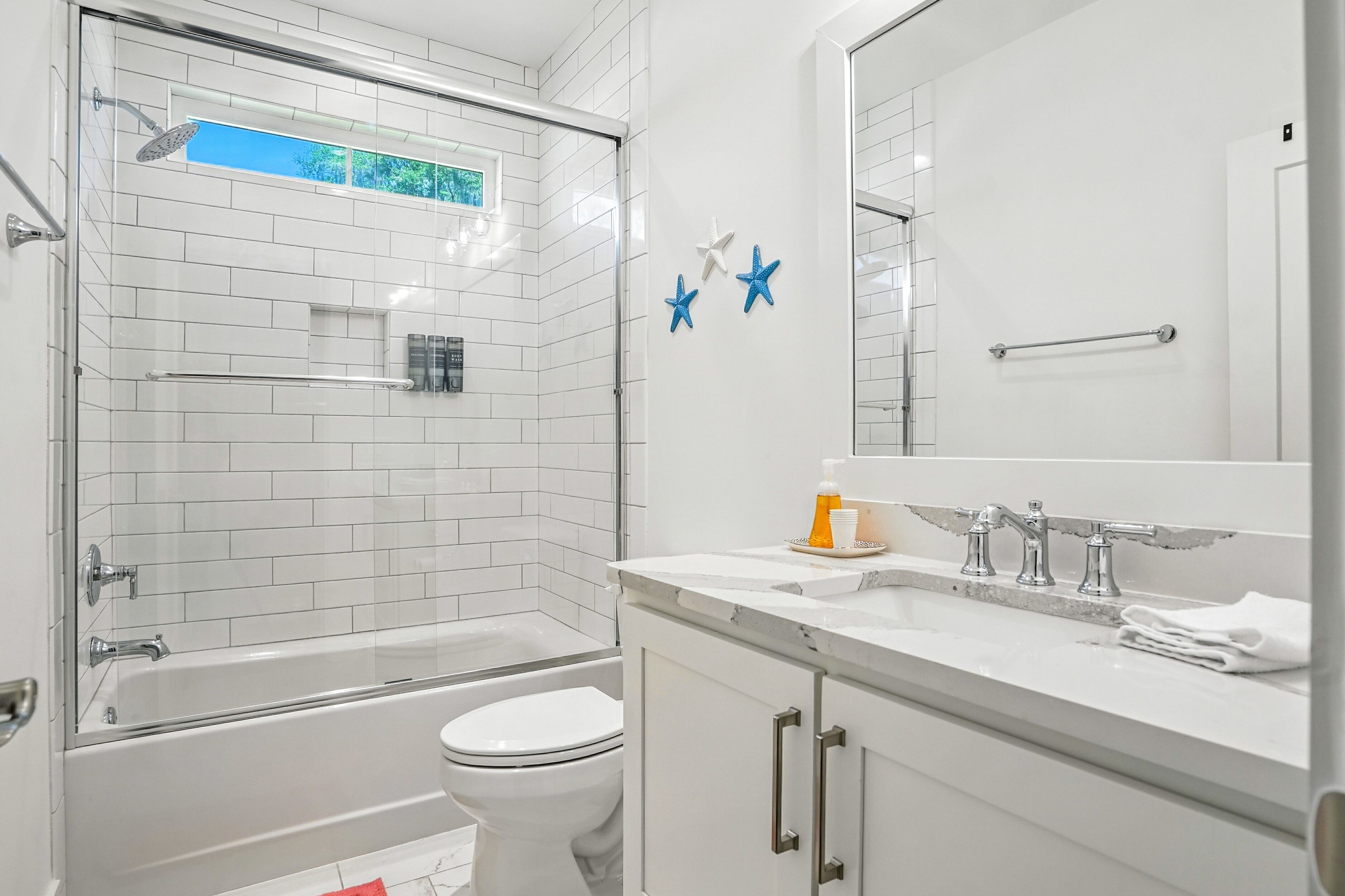 Un baño moderno con ducha envuelta en vidrio, inodoro blanco y tocador con espejo.