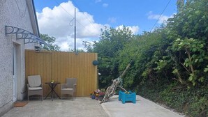A patio area with two wicker chairs, a small round table, and a blue planter with orange flowers. - Peaceful escape in historic Meath near Slane, Tara, Newgrange, and Dublin (Slane)