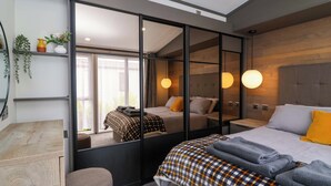 A modern hotel room with a large bed, a desk, and a mirror. - Hazelnut Lodge (Chipping Norton)