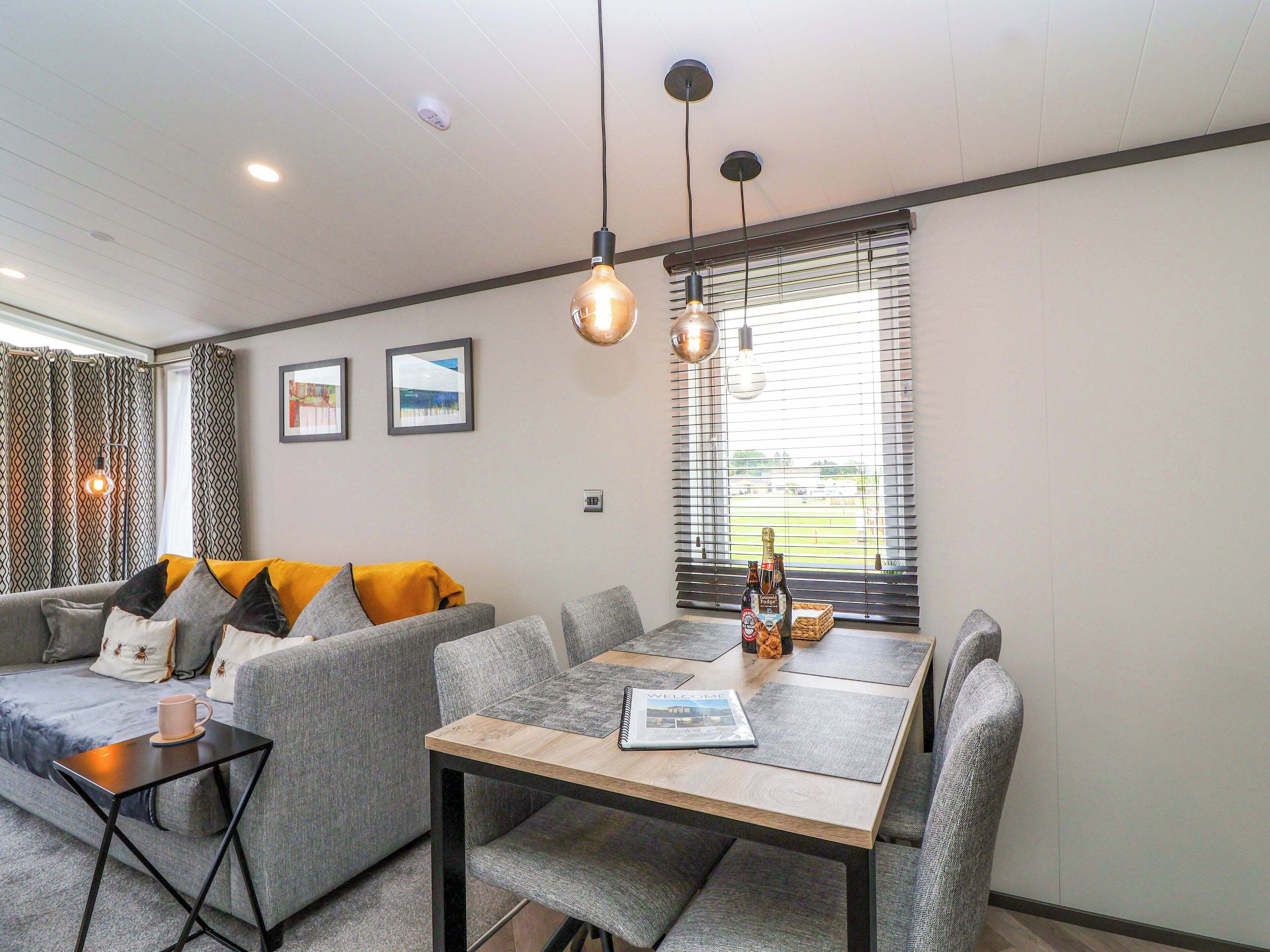 A modern living room with a sofa, a dining table, and a window with blinds.