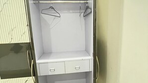 A walk-in closet with a metal frame, two drawers, and a hanging rod. - Hotel Kashi Vaas (Varanasi)