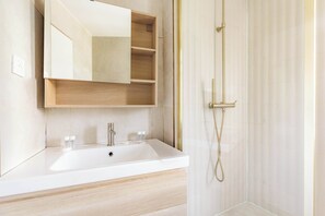 A bathroom with a white sink, a mirror, and a shower.