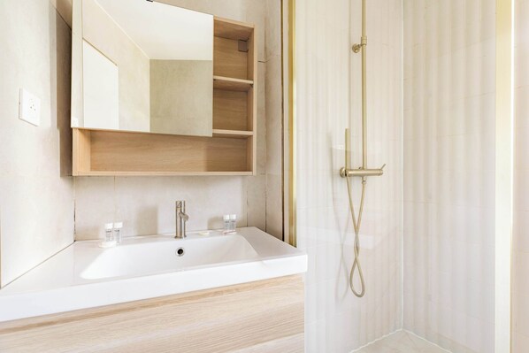 A bathroom with a white sink, a mirror, and a shower.