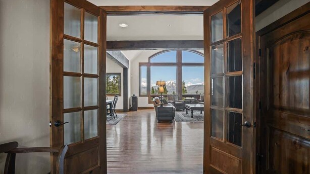 A spacious interior with a large wooden door leading to a room with a view of mountains. - Top Of the World (Crested Butte)