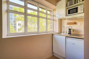 Una cocina con un ventanal grande, microondas, cafetera y lavavajillas.