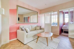 Un salón con sofá, una mesa de centro, un espejo grande y una ventana con cortinas.