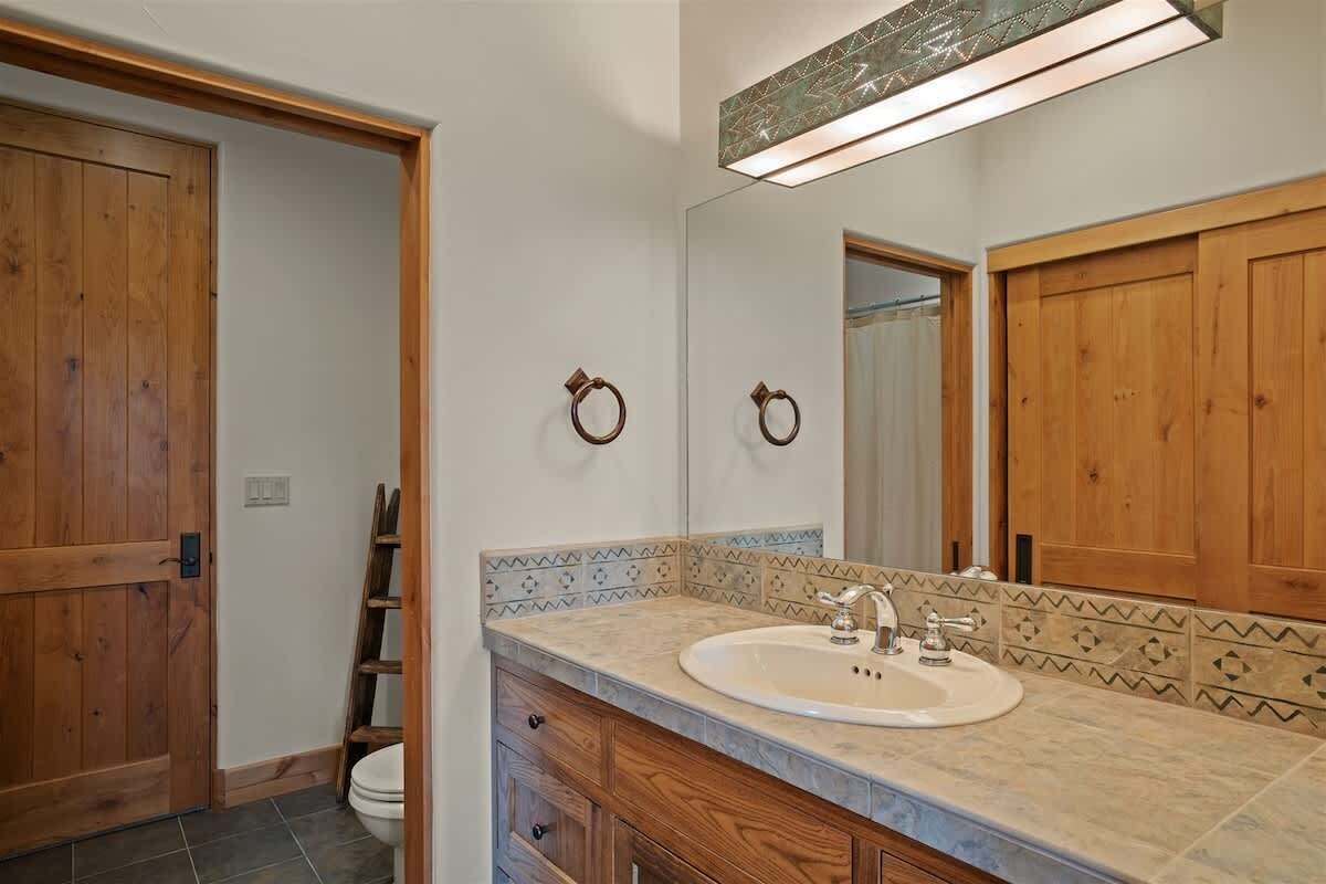 A bathroom with wooden cabinets, a sink, and a mirror.