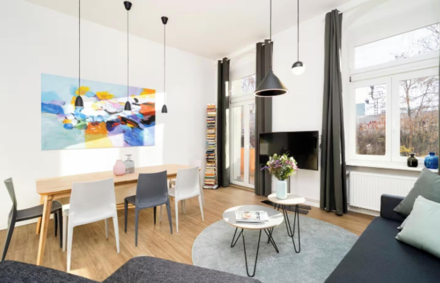 Un salon moderne comprenant un coin repas, un téléviseur à écran plat et un grand tableau abstrait accroché au mur.