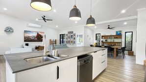 Una cucina moderna con isola centrale, lavastoviglie integrata e illuminazione a sospensione.