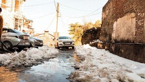 A narrow street with snow and ice, a white car in the distance, and buildings on either side. - Shimla Hill View (Shimla)