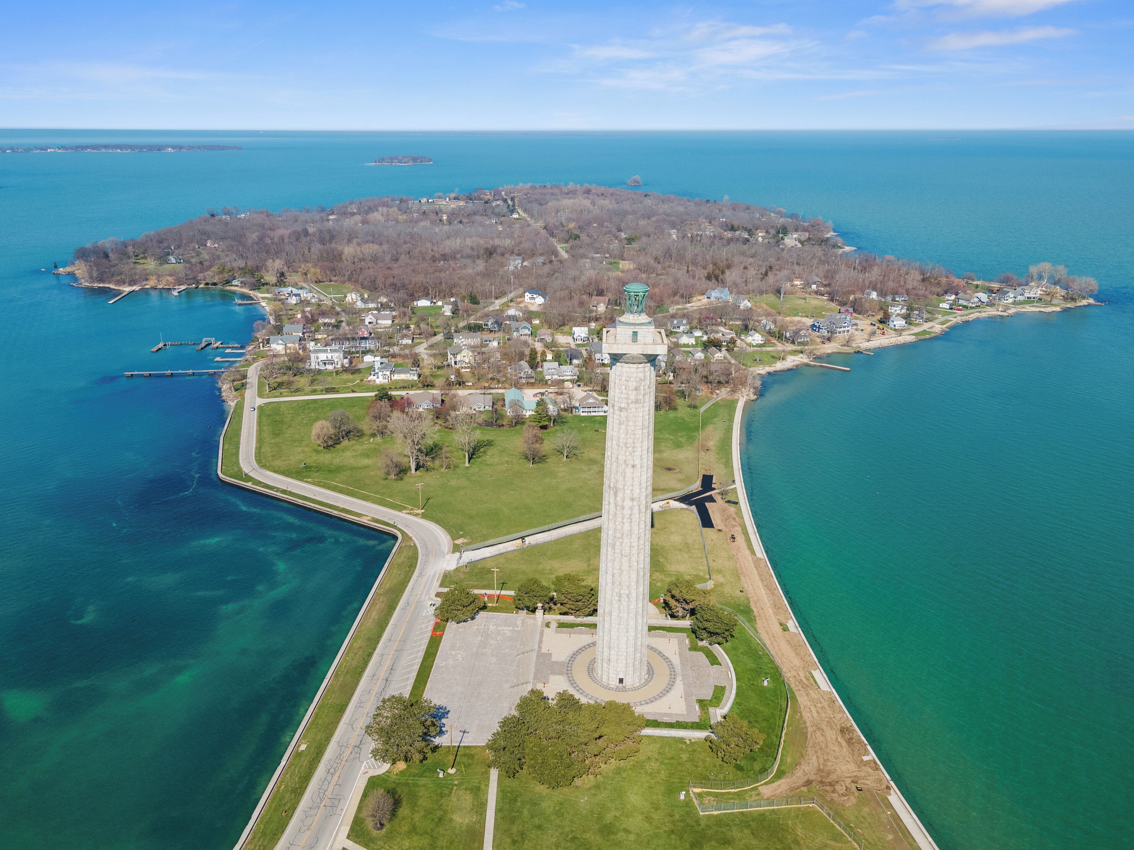 Eine Vogelperspektive einer Küstenstadt mit einem markanten Turm, klarem blauen Wasser und einer kleinen Insel in der Ferne.