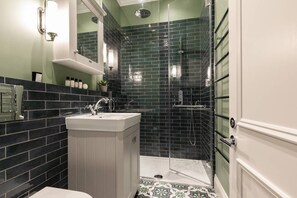 Une salle de bain avec un lavabo blanc, un miroir et un espace douche doté d’une porte en verre.