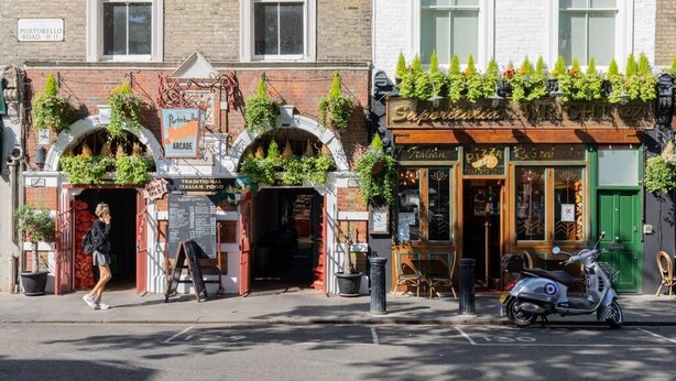 A street view with a building featuring a sign for 'Portobello Arcade' and another for 'Sapore Italiano'. - Westbourne Park Road Xvii by Onefinestay (London)