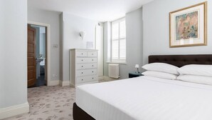 A bedroom with a large bed, a dresser, a nightstand, and a window with blinds. - Drury Lane II by Onefinestay (London)