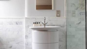Un baño moderno con tocador blanco, un espejo grande y cabina de ducha de vidrio.