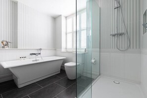 A modern bathroom with a freestanding bathtub, a glass-enclosed shower, and a toilet.