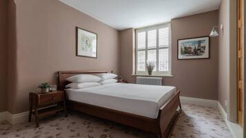 Un dormitorio con una cama de madera, una mesita de noche, una ventana con persianas y dos cuadros en la pared.