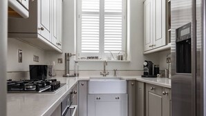 A compact kitchen with white cabinets, a built-in oven, a sink, and a coffee maker. - Drury Lane II by Onefinestay (London)