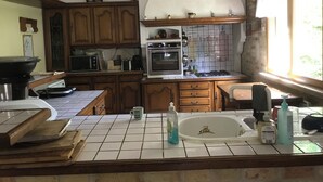 A kitchen with wooden cabinets, a tiled backsplash, a stove, an oven, a microwave, and a sink.